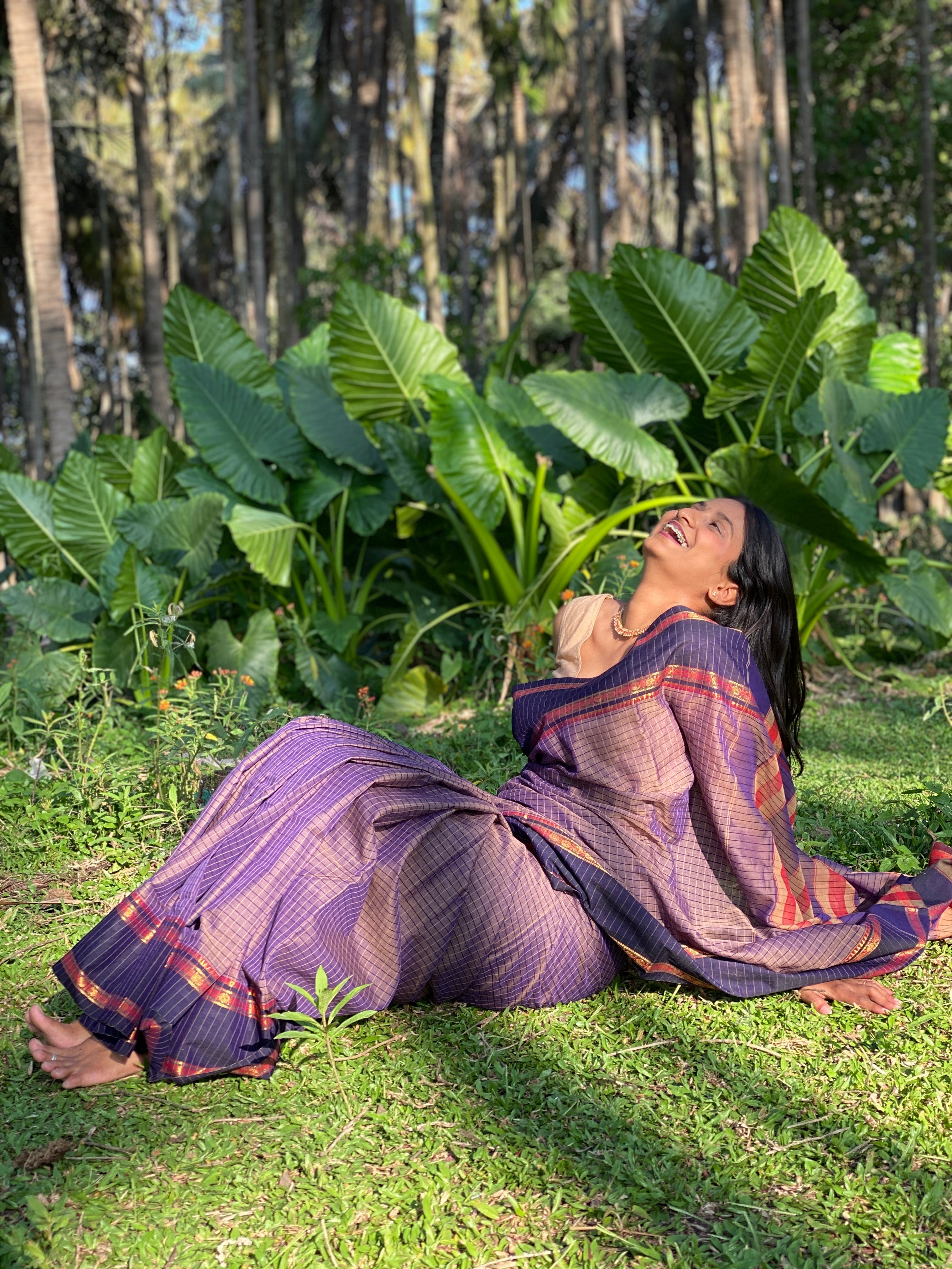 Woman in purple handloom cotton saree sitting on grass